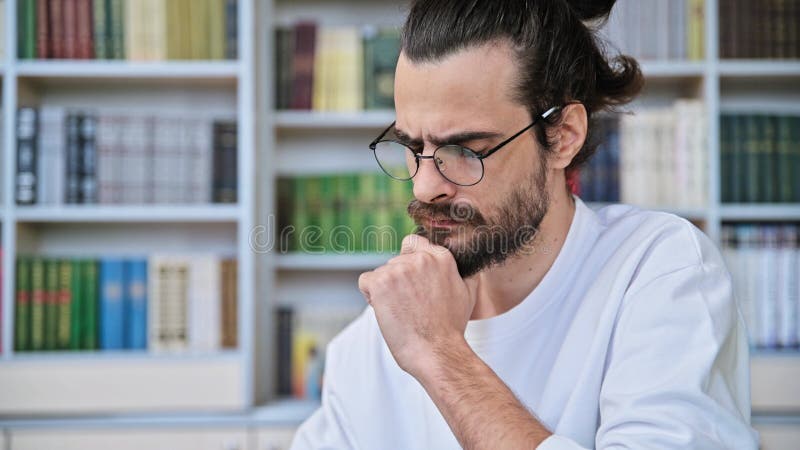 Retrato de la cabeza de un hombre de 30 años inteligente, serio y barbudo, que piensa de la mano en la barbilla metrajes