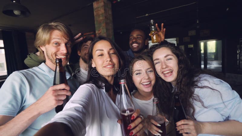Retrato de la cámara lenta de los compañeros de trabajo del grupo de personas que toman el selfie con las bebidas en las fiestas