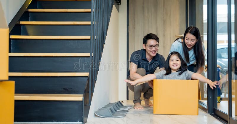 Retrato de la familia asiática feliz que se mueve a la nueva casa con las cajas de cartón y que juega la caja de cartón imagen de archivo libre de regalías Retrato de la familia asiática feliz que se mueve a la nueva casa con las cajas de cartón y que juega la caja de cartón imagen de archivo libre de regalías