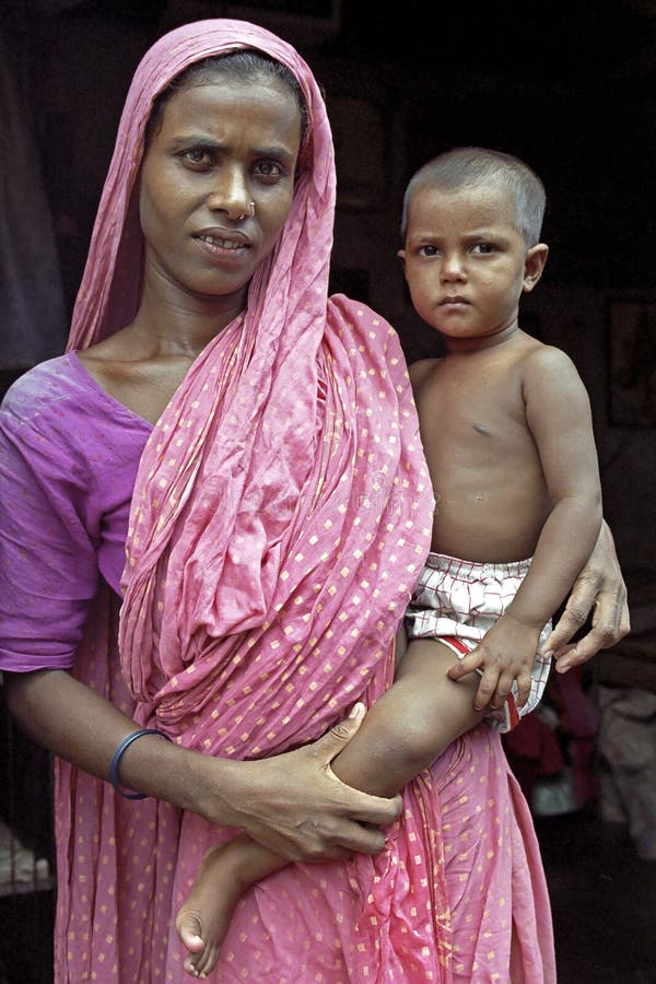 Bangladesh: Group portrait of a woman in traditional colorful dress with a headscarf and nose ring, with her child in her arms in the capital, city Dhaka. She carries the boy on her hip. The woman looks with a shy smile and the toddler expressionless straight into the camera. Bangladesh: Group portrait of a woman in traditional colorful dress with a headscarf and nose ring, with her child in her arms in the capital, city Dhaka. She carries the boy on her hip. The woman looks with a shy smile and the toddler expressionless straight into the camera.