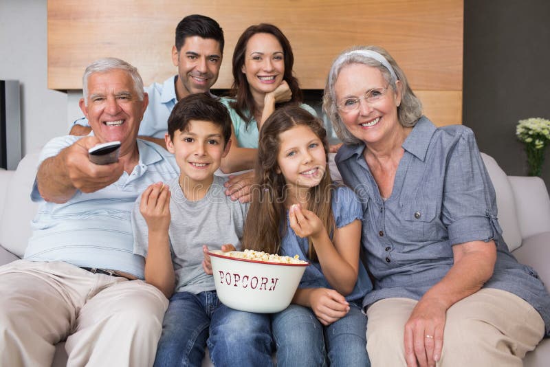 Retrato de la familia extensa feliz que ve la TV en sala de estar foto de archivo Retrato de la familia extensa feliz que ve la TV en sala de estar foto de archivo