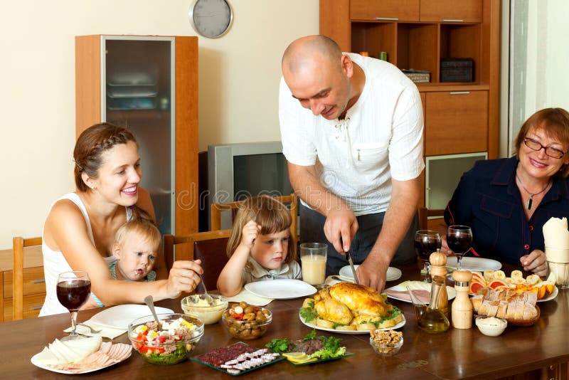 Retrato de la familia multigeneración feliz que come el pollo con los wi foto de archivo libre de regalías Retrato de la familia multigeneración feliz que come el pollo con los wi foto de archivo libre de regalías