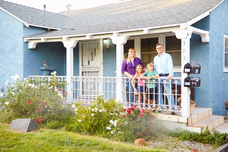 Portrait Of Happy Family Standing Outside On Porch Of Suburban Home. Portrait Of Happy Family Standing Outside On Porch Of Suburban Home