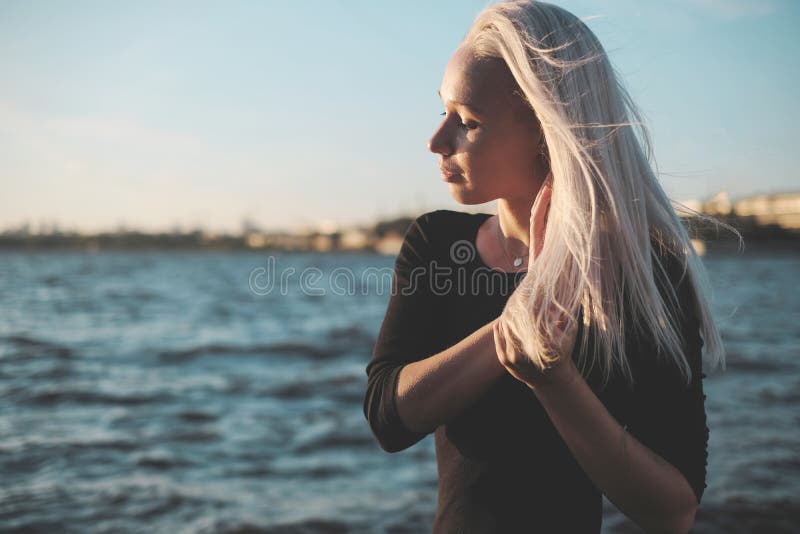 Retrato de la forma de vida de la mujer rubia joven en día ventoso en la puesta del sol imagen de archivo Retrato de la forma de vida de la mujer rubia joven en día ventoso en la puesta del sol imagen de archivo