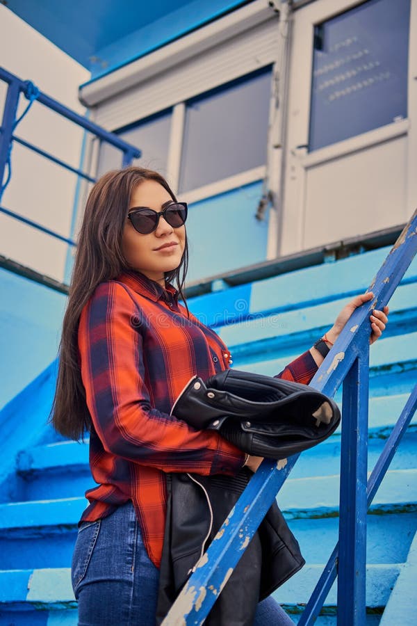 Retrato De La Hembra Morena En Gafas De Sol Sobre Las Escaleras Azules