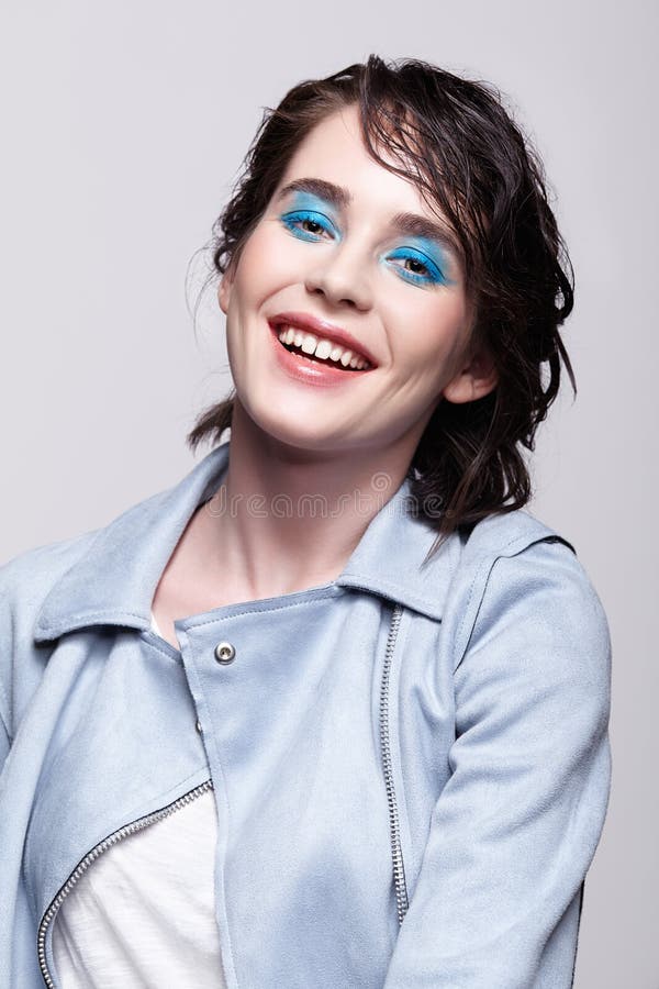 Retrato de la hembra sonriente en chaqueta azul Mujer con maquillaje inusual de la belleza y pelo mojado, y maquillaje azul de la fotografía de archivo libre de regalías Retrato de la hembra sonriente en chaqueta azul Mujer con maquillaje inusual de la belleza y pelo mojado, y maquillaje azul de la fotografía de archivo libre de regalías
