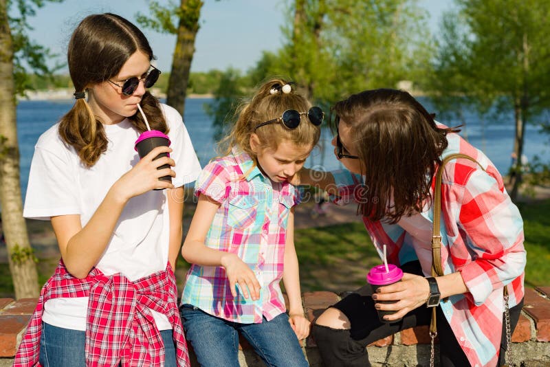 Retrato de la madre y de dos años de las hijas 14 y 8, comunicando en parque en naturaleza imagenes de archivo Retrato de la madre y de dos años de las hijas 14 y 8, comunicando en parque en naturaleza imagenes de archivo