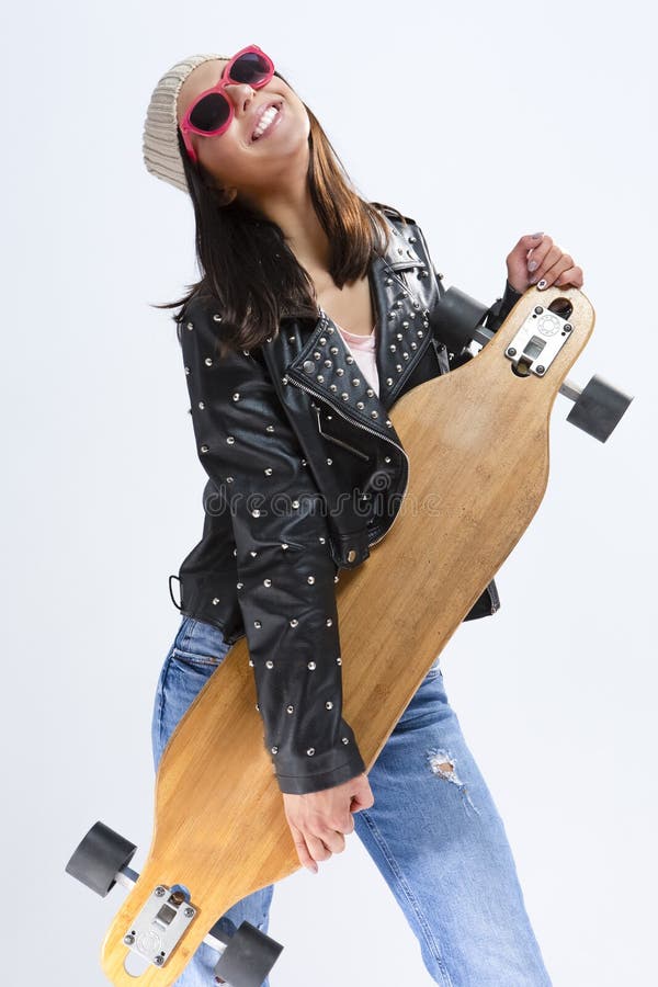 Retrato de la morenita caucásica sonriente feliz en chaqueta de cuero negra y las gafas de sol que presentan con Longboard imágenes de archivo libres de regalías Retrato de la morenita caucásica sonriente feliz en chaqueta de cuero negra y las gafas de sol que presentan con Longboard imágenes de archivo libres de regalías