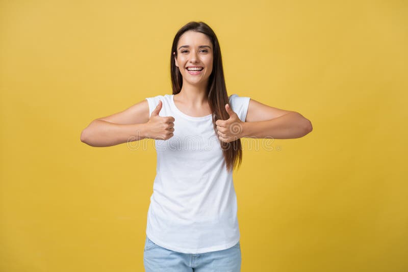 Retrato de la muchacha alegre linda hermosa joven que sonríe mirando la cámara sobre fondo amarillo Gesto de los pulgares imagen de archivo Retrato de la muchacha alegre linda hermosa joven que sonríe mirando la cámara sobre fondo amarillo Gesto de los pulgares imagen de archivo