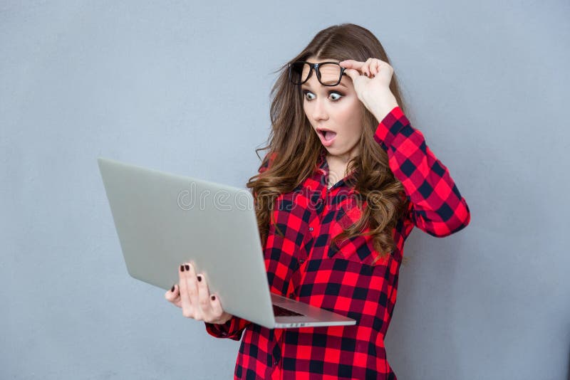 Retrato de la muchacha chocada con la boca abierta usando el ordenador portátil fotos de archivo libres de regalías Retrato de la muchacha chocada con la boca abierta usando el ordenador portátil fotos de archivo libres de regalías