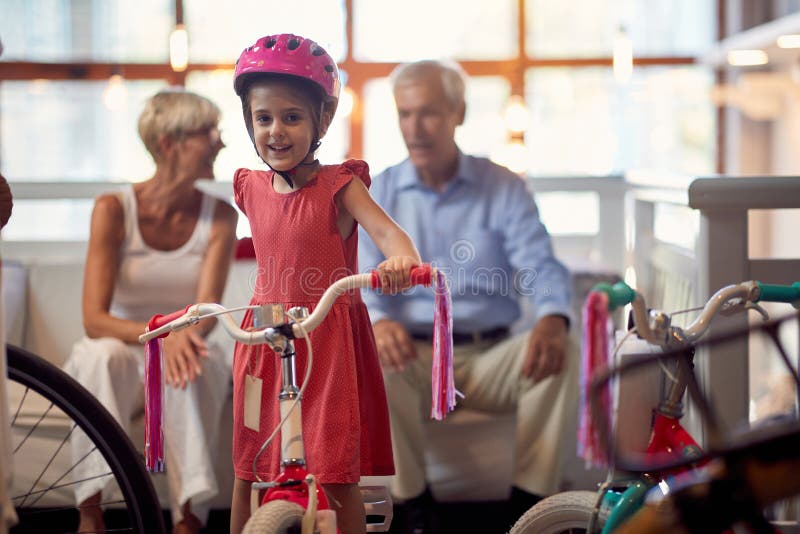 Retrato de la muchacha del niño que se sienta en la bicicleta en tienda de la bici imagen de archivo Retrato de la muchacha del niño que se sienta en la bicicleta en tienda de la bici imagen de archivo