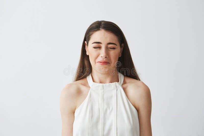 Retrato de la muchacha morena joven descontentada que hace la cara divertida sobre el fondo blanco fotos de archivo libres de regalías Retrato de la muchacha morena joven descontentada que hace la cara divertida sobre el fondo blanco fotos de archivo libres de regalías