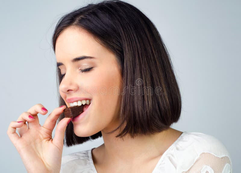 Retrato de la muchacha sonriente hermosa que come las galletas del chocolate imágenes de archivo libres de regalías Retrato de la muchacha sonriente hermosa que come las galletas del chocolate imágenes de archivo libres de regalías