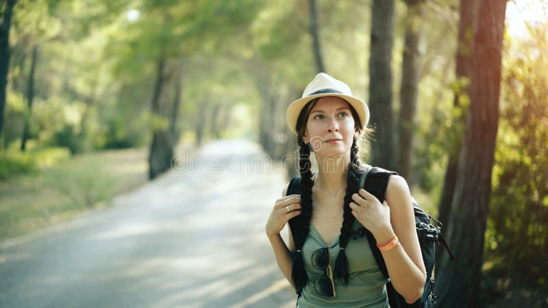 Retrato de la muchacha turística atractiva que sonríe y que mira en cámara mientras que camina y camina el bosque hermoso fotografía de archivo libre de regalías Retrato de la muchacha turística atractiva que sonríe y que mira en cámara mientras que camina y camina el bosque hermoso fotografía de archivo libre de regalías