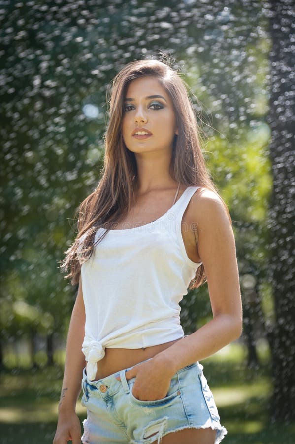 Retrato de la mujer atractiva en el espray del agua con la camiseta blanca Ella tiene una buena piel apacible, postura sensual, y fotos de archivo Retrato de la mujer atractiva en el espray del agua con la camiseta blanca Ella tiene una buena piel apacible, postura sensual, y fotos de archivo