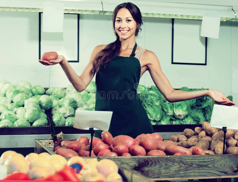 Retrato de la mujer en el delantal que vende las patatas orgánicas en tienda foto de archivo libre de regalías Retrato de la mujer en el delantal que vende las patatas orgánicas en tienda foto de archivo libre de regalías