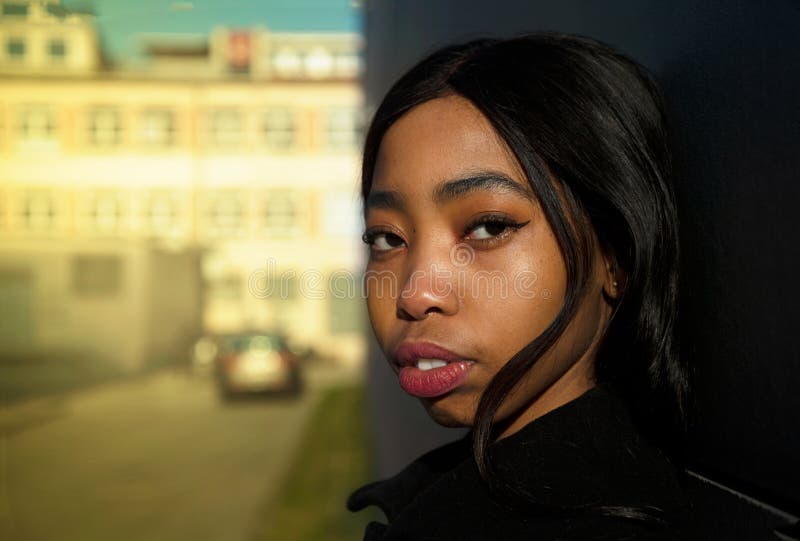Retrato de la mujer joven africana americana con el edificio de la falta de definición y del coche en la calle de la ciudad imagen de archivo Retrato de la mujer joven africana americana con el edificio de la falta de definición y del coche en la calle de la ciudad imagen de archivo