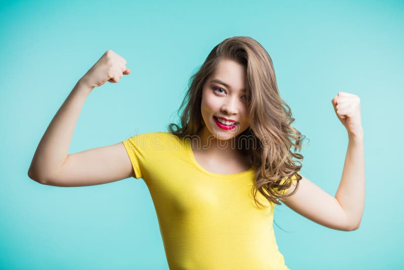 Retrato de la mujer joven alegre que aumenta sus puños con la cara encantada sonriente, sí gesto foto de archivo libre de regalías Retrato de la mujer joven alegre que aumenta sus puños con la cara encantada sonriente, sí gesto foto de archivo libre de regalías