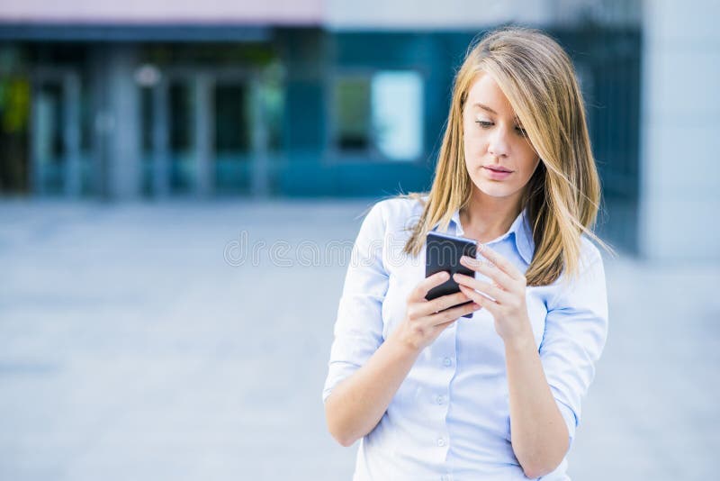 Retrato de la mujer joven alegre que habla en smartphone y que ríe al aire libre imagen de archivo Retrato de la mujer joven alegre que habla en smartphone y que ríe al aire libre imagen de archivo
