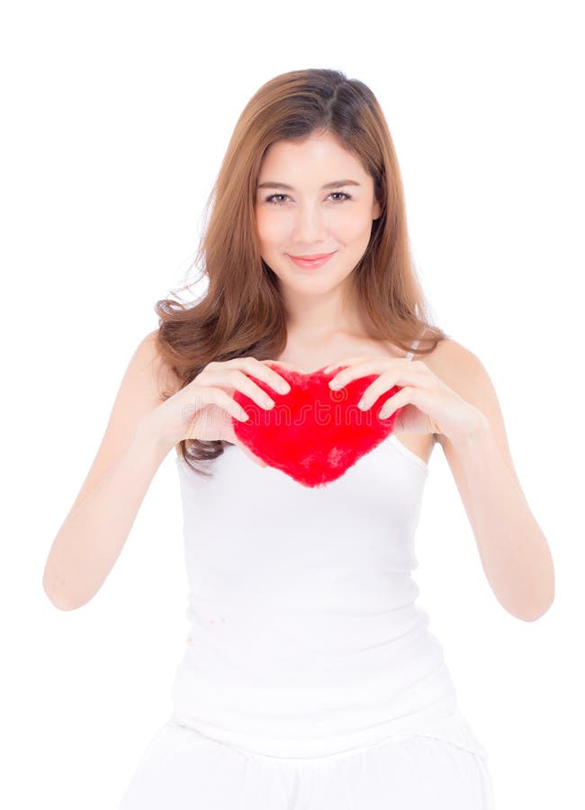 Retrato de la mujer joven asi?tica hermosa que celebra la almohada roja y la sonrisa de la forma del coraz?n aislado en el fondo fotografía de archivo libre de regalías Retrato de la mujer joven asi?tica hermosa que celebra la almohada roja y la sonrisa de la forma del coraz?n aislado en el fondo fotografía de archivo libre de regalías