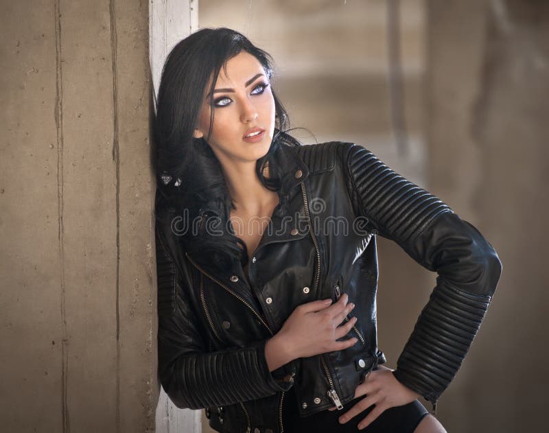Retrato de la mujer joven atractiva hermosa con el equipo negro, chaqueta de cuero sobre la ropa interior, en fondo urbano foto de archivo Retrato de la mujer joven atractiva hermosa con el equipo negro, chaqueta de cuero sobre la ropa interior, en fondo urbano foto de archivo