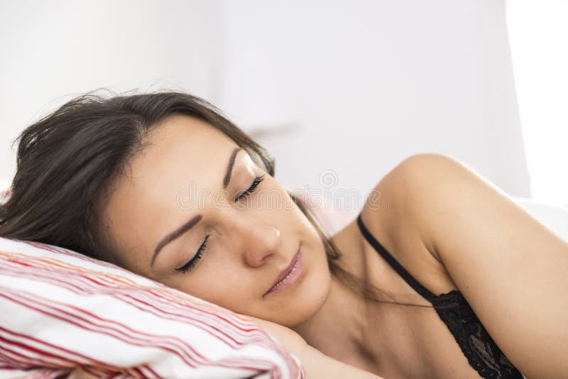 Retrato de la mujer joven hermosa que duerme en la cama blanca imagen de archivo Retrato de la mujer joven hermosa que duerme en la cama blanca imagen de archivo