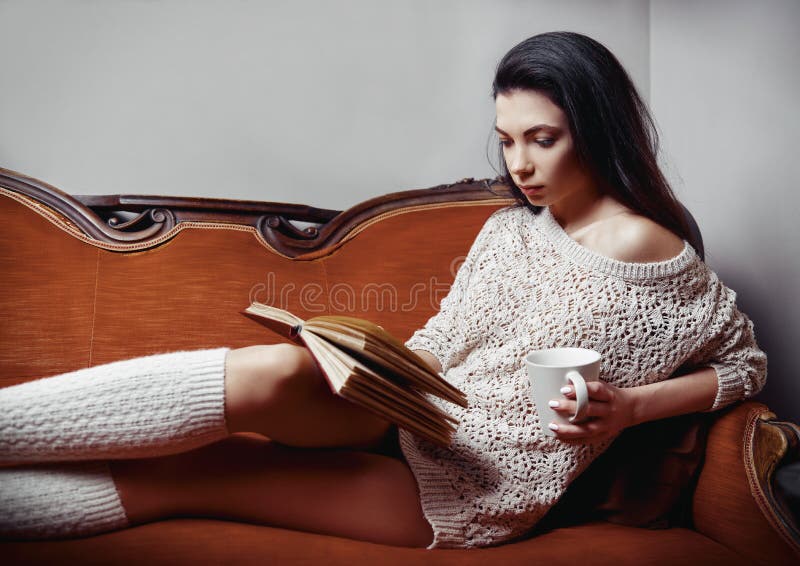 Retrato de la mujer joven hermosa vestida en calcetines del suéter y de la rodilla Muchacha de fascinación con la taza a disposic fotografía de archivo Retrato de la mujer joven hermosa vestida en calcetines del suéter y de la rodilla Muchacha de fascinación con la taza a disposic fotografía de archivo