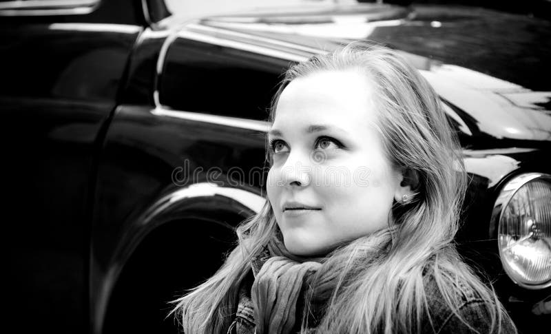 Retrato de la mujer joven que se sienta contra el coche retro imagen de archivo Retrato de la mujer joven que se sienta contra el coche retro imagen de archivo