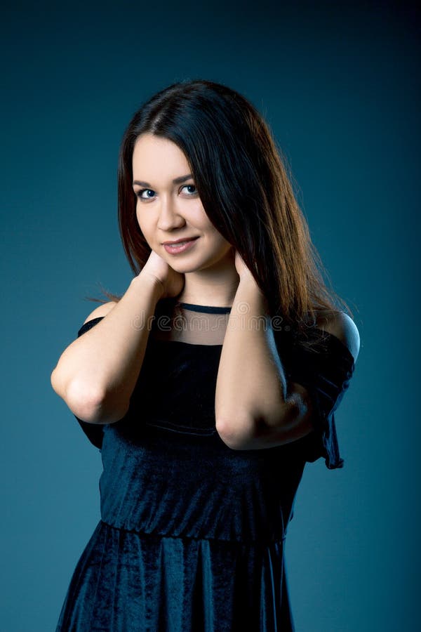 Retrato de la mujer morena bastante joven en vestido negro Estudio tirado sobre fondo del gris azul imagen de archivo Retrato de la mujer morena bastante joven en vestido negro Estudio tirado sobre fondo del gris azul imagen de archivo