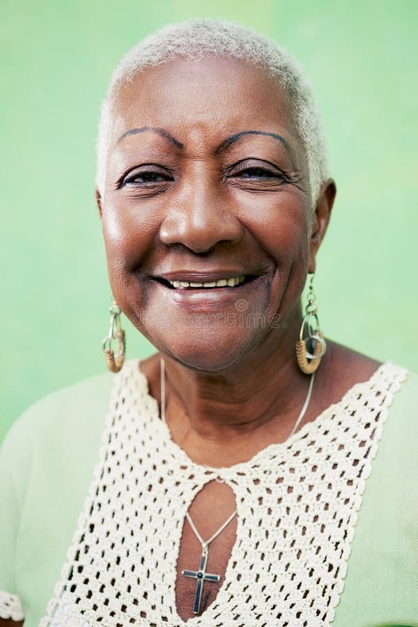 Retrato de la mujer negra mayor que sonríe en la cámara en backgr verde imagenes de archivo