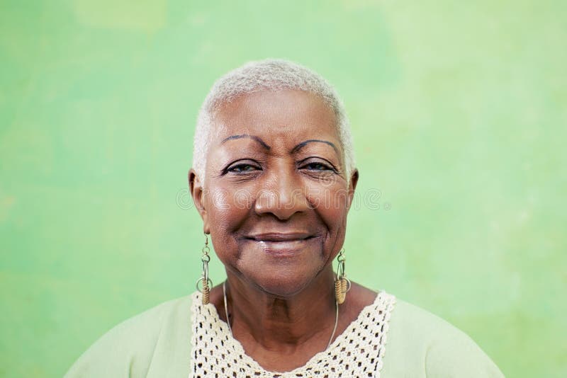 Retrato de la mujer negra mayor que sonríe en la cámara en backgr verde fotografía de archivo