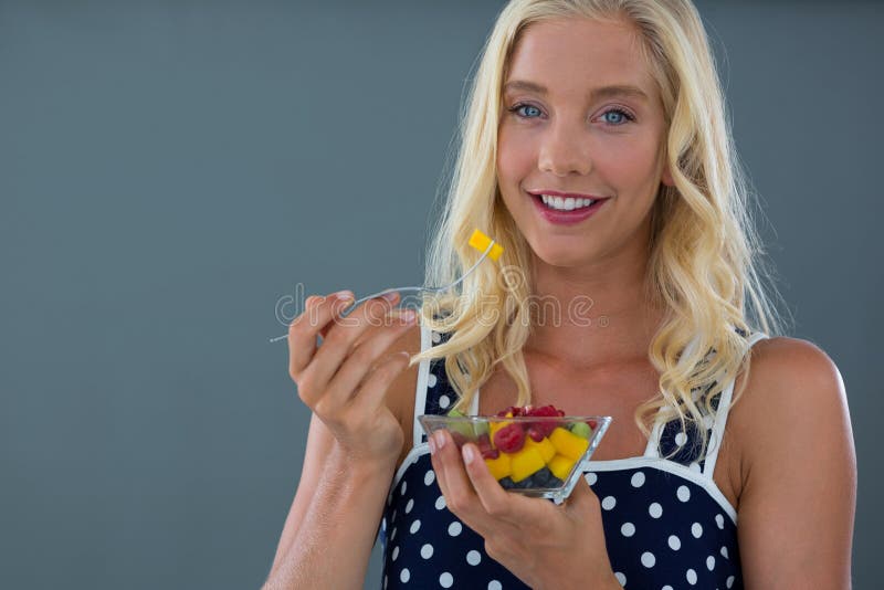 Retrato de la mujer que come la ensalada de fruta en cuenco imagenes de archivo Retrato de la mujer que come la ensalada de fruta en cuenco imagenes de archivo