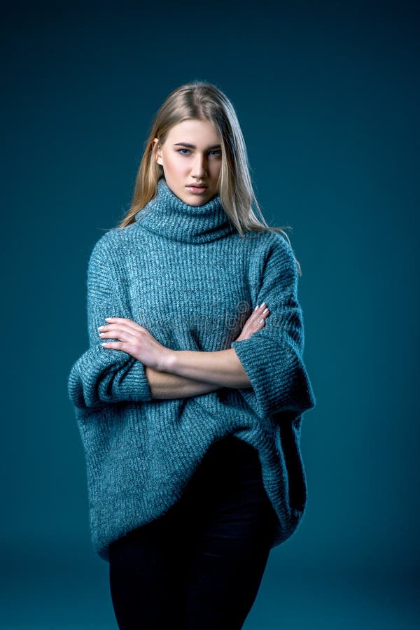 Retrato de la mujer rubia hermosa adentro en el suéter blanco sobre fondo azul gris imagenes de archivo Retrato de la mujer rubia hermosa adentro en el suéter blanco sobre fondo azul gris imagenes de archivo