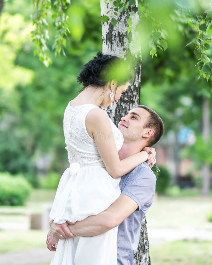 Retrato de la novia femenina de los pares jovenes hermosos y del novio del varón que abrazan y que miran uno a en parque del vera fotos de archivo Retrato de la novia femenina de los pares jovenes hermosos y del novio del varón que abrazan y que miran uno a en parque del vera fotos de archivo
