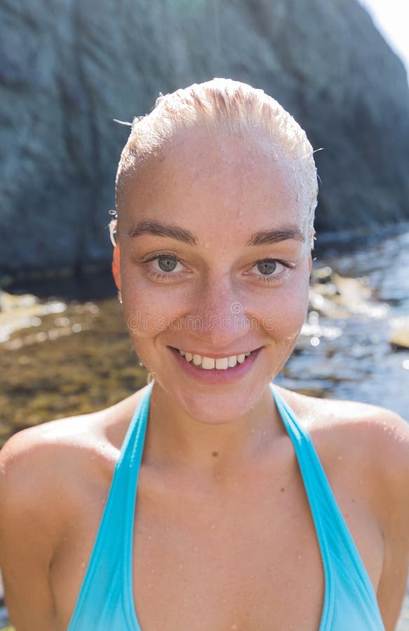 Retrato de la persona femenina atractiva con el pelo slicked mojado contra la playa rocosa fotos de archivo libres de regalías Retrato de la persona femenina atractiva con el pelo slicked mojado contra la playa rocosa fotos de archivo libres de regalías