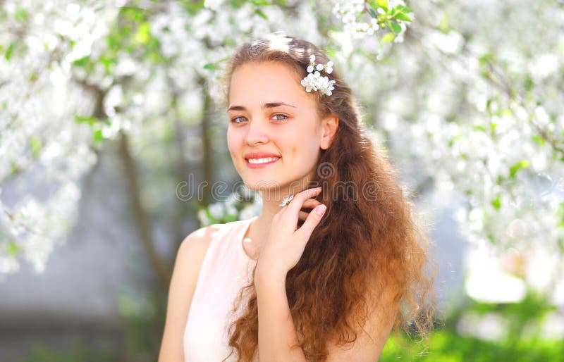 Retrato de la primavera de la chica joven hermosa con el pelo rizado en jardín floreciente imágenes de archivo libres de regalías Retrato de la primavera de la chica joven hermosa con el pelo rizado en jardín floreciente imágenes de archivo libres de regalías