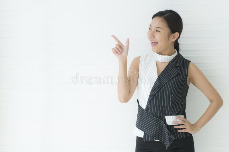 Retrato de linda jovem asiática alegre apontando o dedo para longe com espaço de cópia no estúdio Isolado sobre fundo branco foto de stock Retrato de linda jovem asiática alegre apontando o dedo para longe com espaço de cópia no estúdio Isolado sobre fundo branco foto de stock