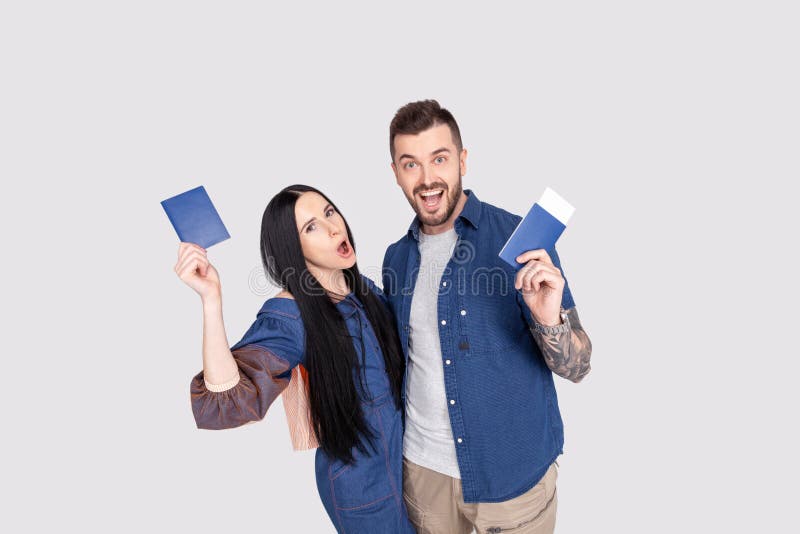Retrato de los pares alegres alegres que sostienen el pasaporte con los boletos del vuelo en las manos que miran la cámara aislad imágenes de archivo libres de regalías Retrato de los pares alegres alegres que sostienen el pasaporte con los boletos del vuelo en las manos que miran la cámara aislad imágenes de archivo libres de regalías