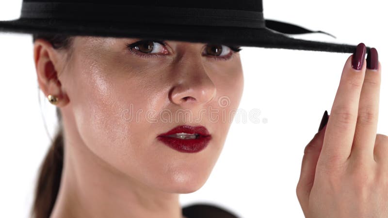 Retrato de mujer adulta en sombrero en estudio blanco. femme fatale traje elegante traje sexy con sombrero de moda de bordes ancho almacen de video