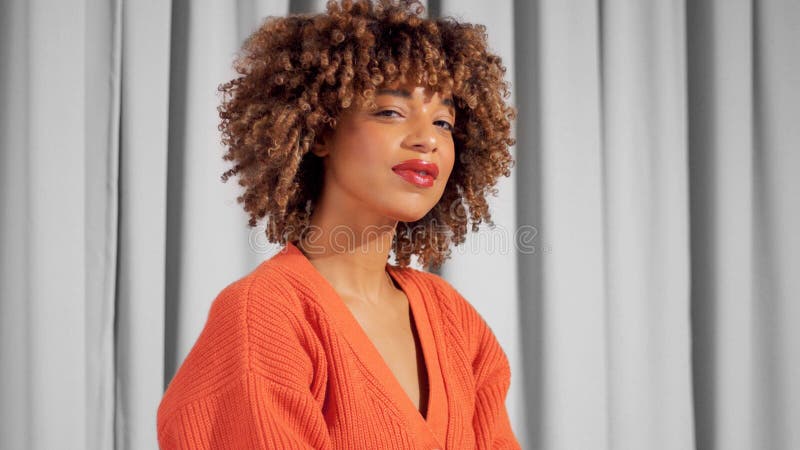Retrato Mujer Adulta Negra De Raza Mixta Con Cortinas Grises Con Chaqueta De Punto Naranja Brillante Foto archivo - Imagen de estudio, mujer: