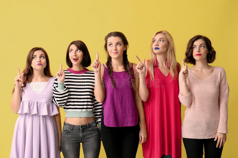 Retrato de mujeres hermosas con los dedos índices aumentados en fondo del color foto de archivo Retrato de mujeres hermosas con los dedos índices aumentados en fondo del color foto de archivo