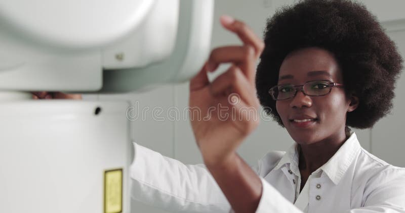 Retrato de médico profesional de etnia africana sonriendo a la cámara. en el hospital el técnico femenino ajusta xray almacen de metraje de vídeo