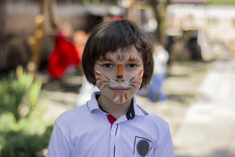 Retrato de niño gracioso con pintura facial sobre fondo borroso