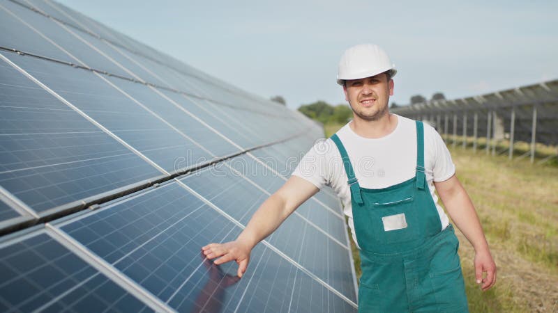 Retrato de orgulloso trabajador industrial ingeniero en uniforme de pie en el campo con grandes baterías solares. granja ecológica