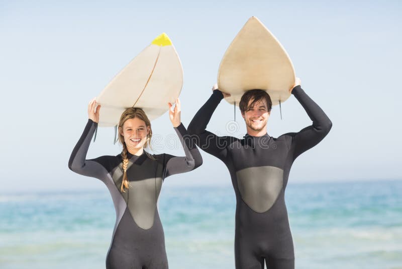 Retrato de pares en gastos indirectos de la tabla hawaiana del wetsuit que llevan imagen de archivo Retrato de pares en gastos indirectos de la tabla hawaiana del wetsuit que llevan imagen de archivo