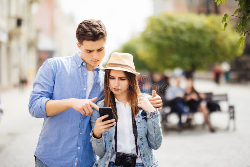 Retrato de pares jovenes del turista en ciudad usando el teléfono móvil en nueva ciudad imagen de archivo libre de regalías Retrato de pares jovenes del turista en ciudad usando el teléfono móvil en nueva ciudad imagen de archivo libre de regalías