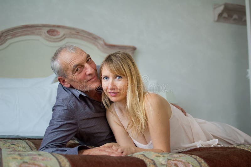 Retrato de pares sonrientes con diferencia de la edad Mujer joven hermosa con su amante mayor que miente en la cama Hombre imagen de archivo libre de regalías Retrato de pares sonrientes con diferencia de la edad Mujer joven hermosa con su amante mayor que miente en la cama Hombre imagen de archivo libre de regalías