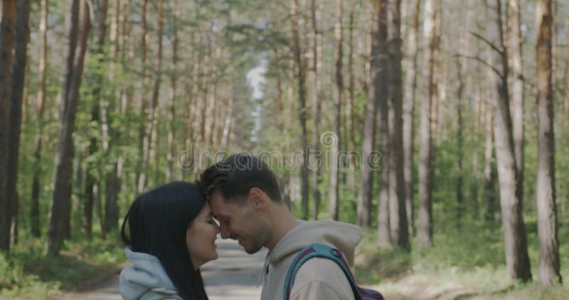 Retrato de tiltdown de novia y novio parados cara a cara expresando amor y felicidad en el bosque en verano