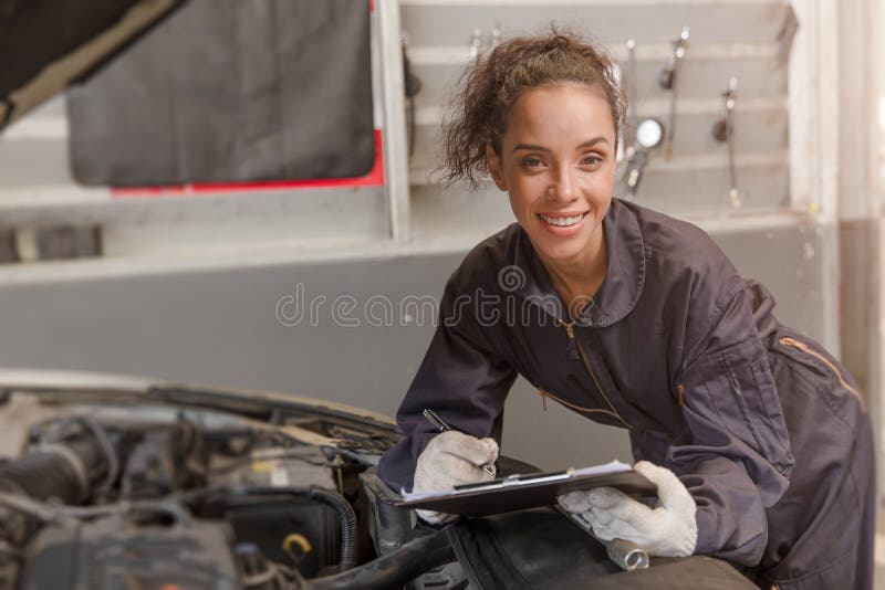 Portrait happy worker African American woman work for auto mechanic in garage checking car engine. Portrait happy worker African American woman work for auto mechanic in garage checking car engine.