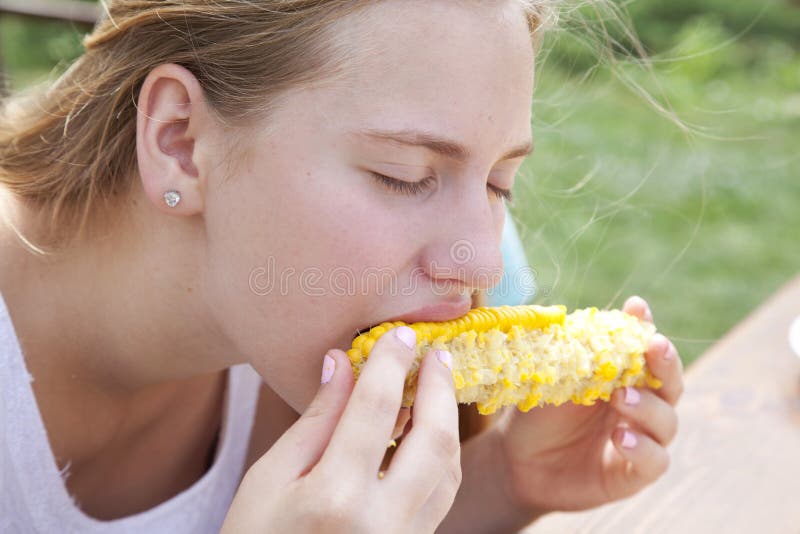 Portrait of a teenage girl eating sweet boiled corn. Young girl on a summer afternoon outdoors. Portrait of a teenage girl eating sweet boiled corn. Young girl on a summer afternoon outdoors